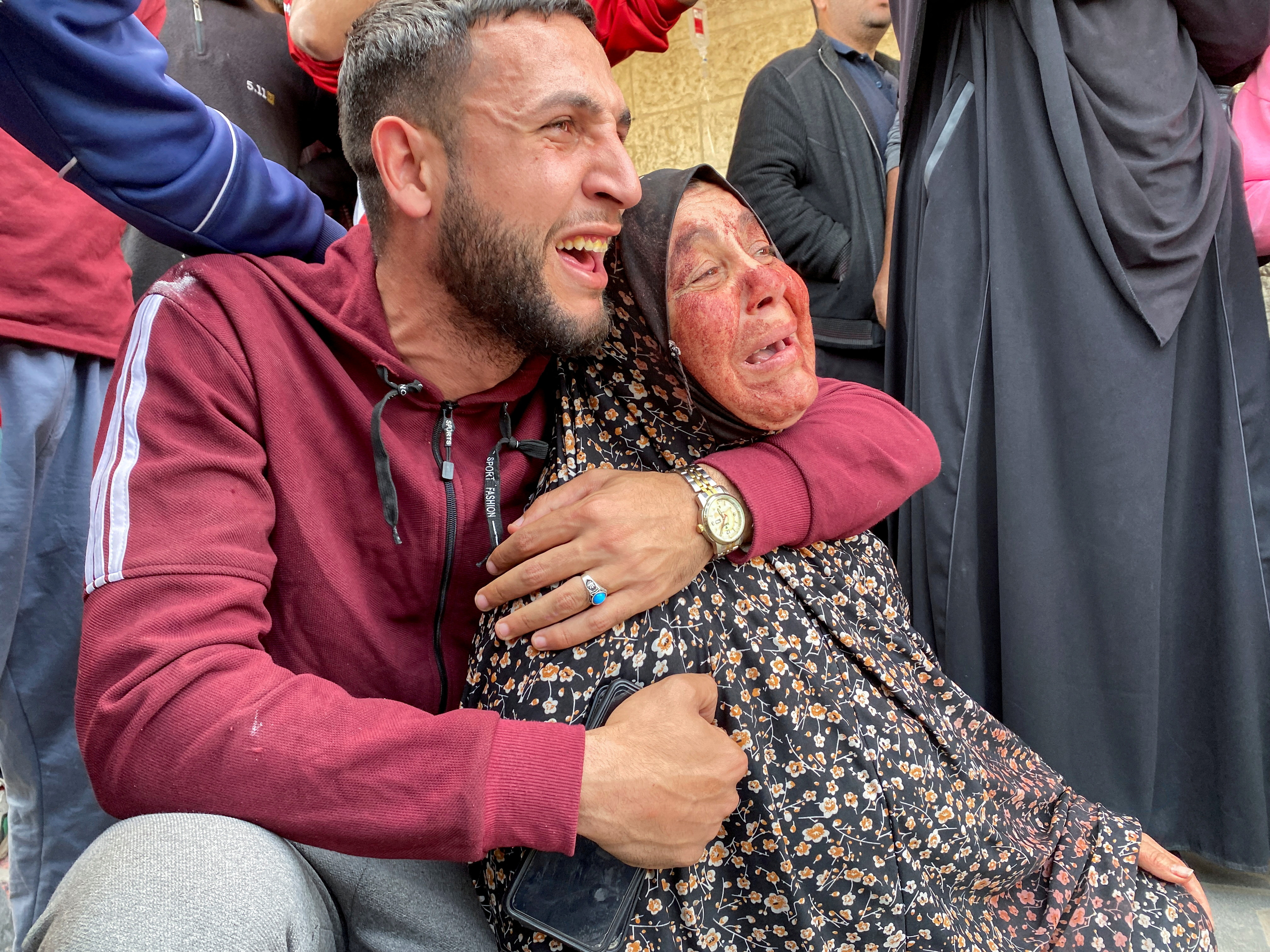 The mother of Palestinian Khalil Abu Shamala, who was killed in an Israeli strike, mourns with her face stained with his blood as Khalil's brother reacts