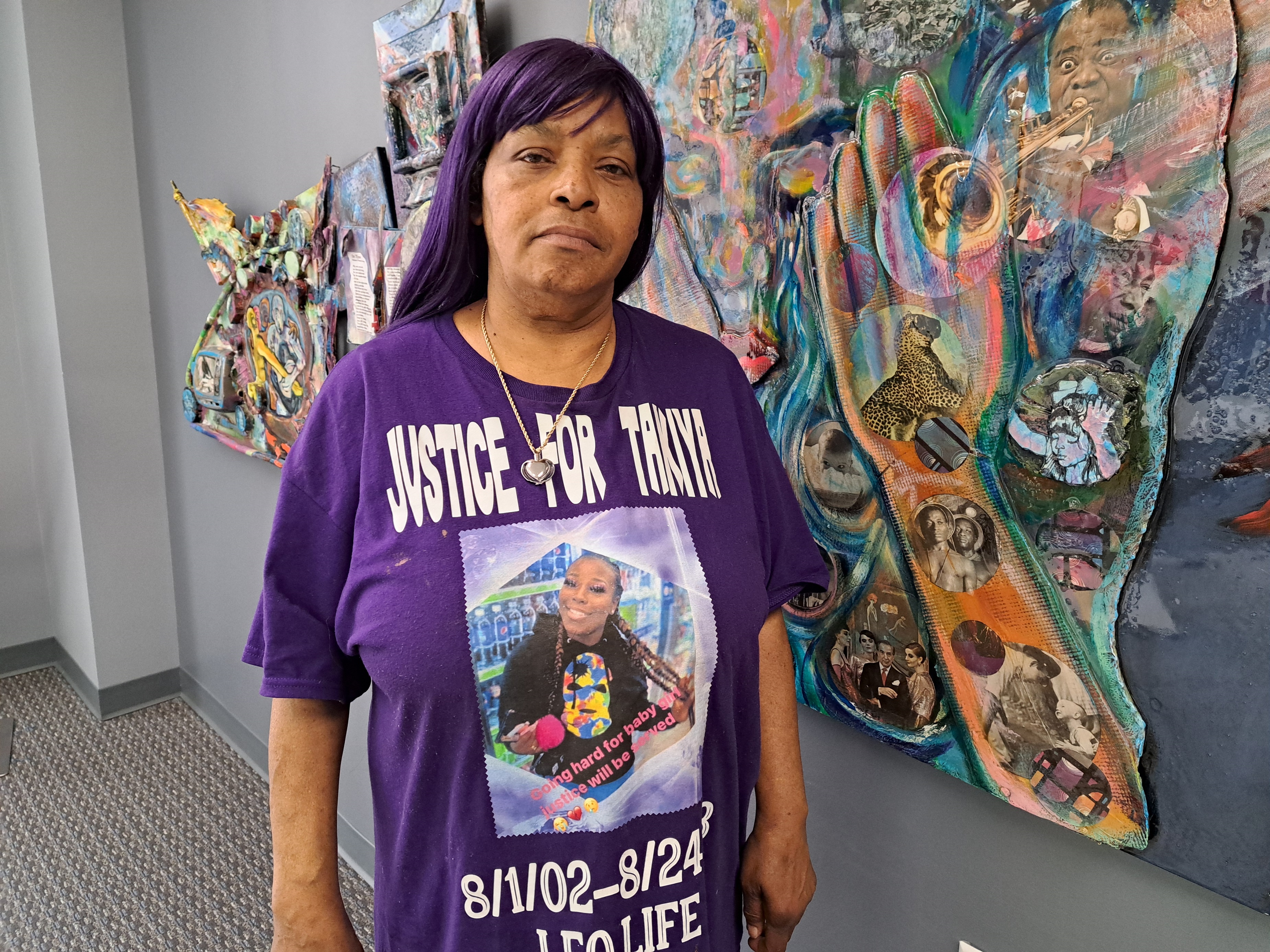 Nadine Young wears a Justice for Ta'Kiya T-shirt as she stands in front of a mural.