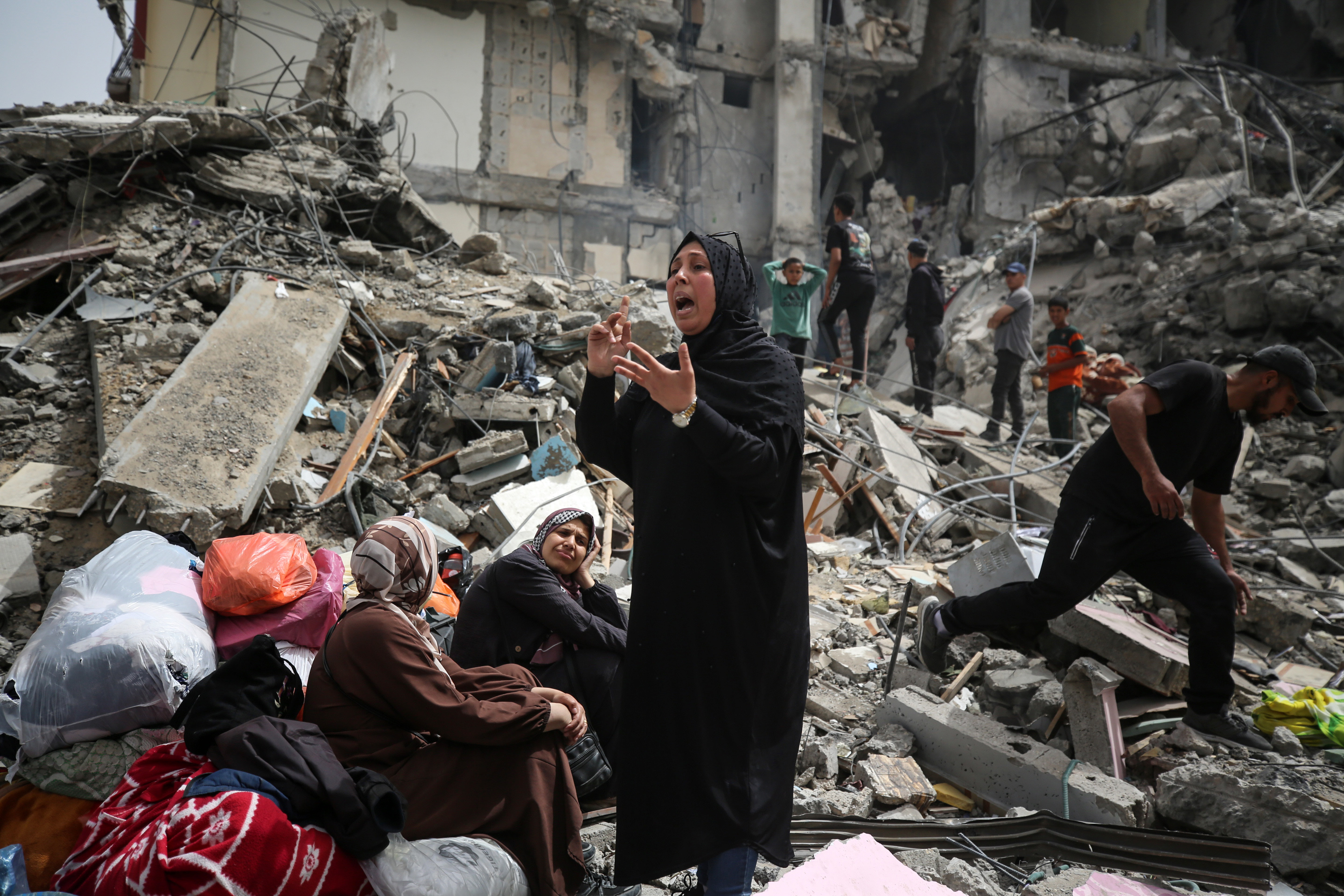 Palestinian women are reacting as they sit on the rubble of a residential building that housed their apartments