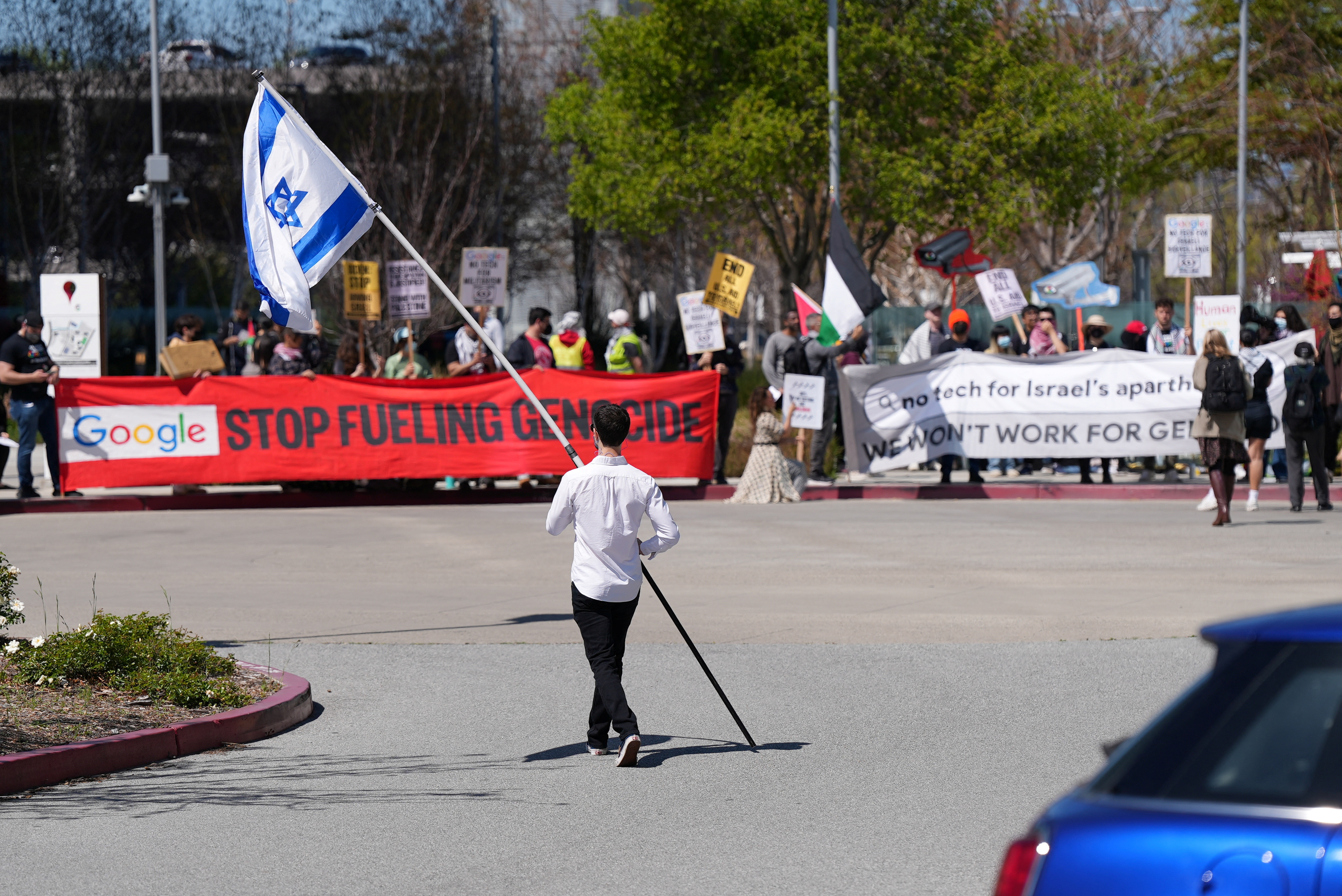 A counter-protester holding an Israeli flag walks into the car park near a protest at Google Cloud offices in Sunnyvale, California on April 16, 2024 [File: Reuters/Nathan Frandino]
