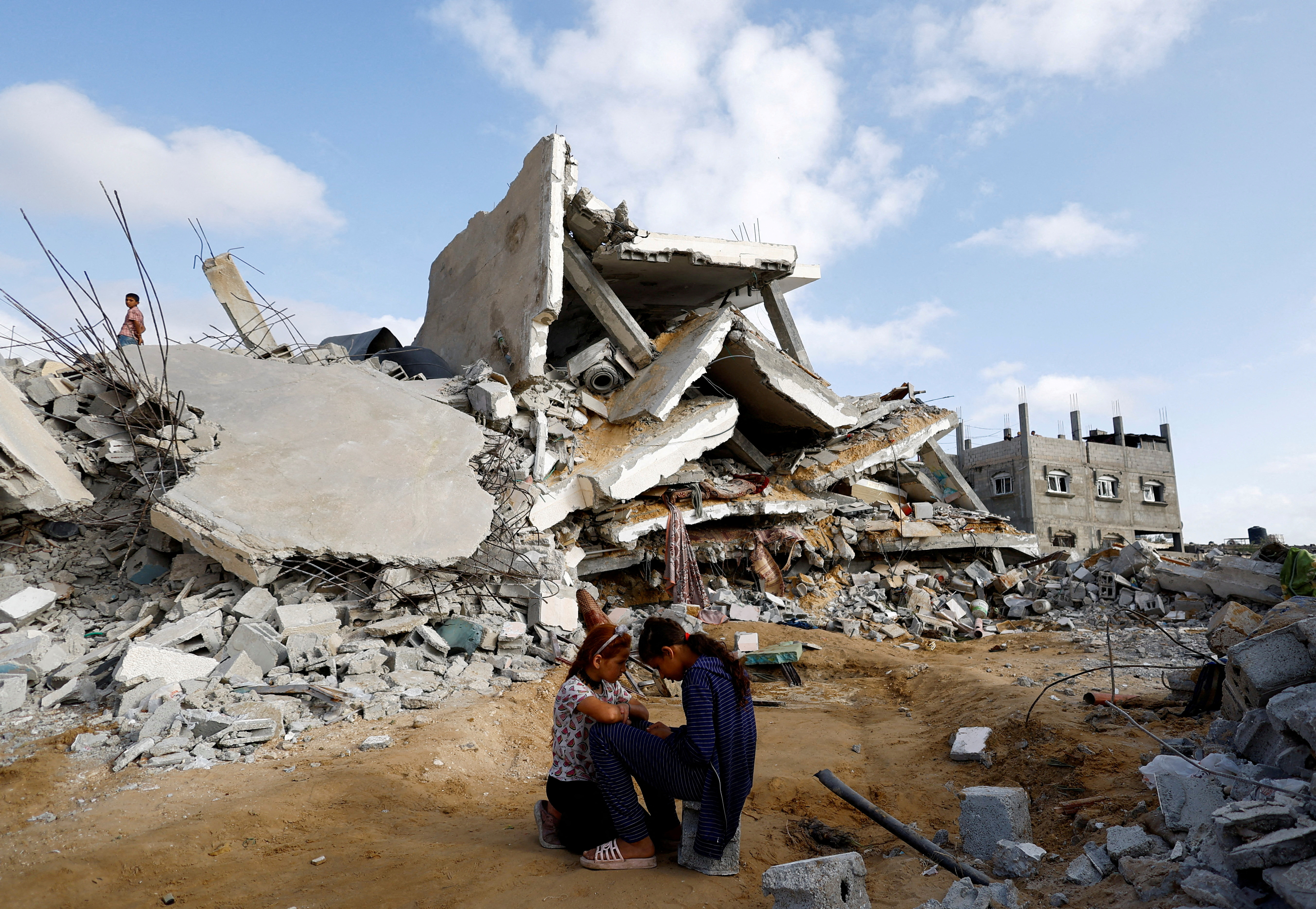 Palestinian children sit next to the site of an Israeli strike on a house