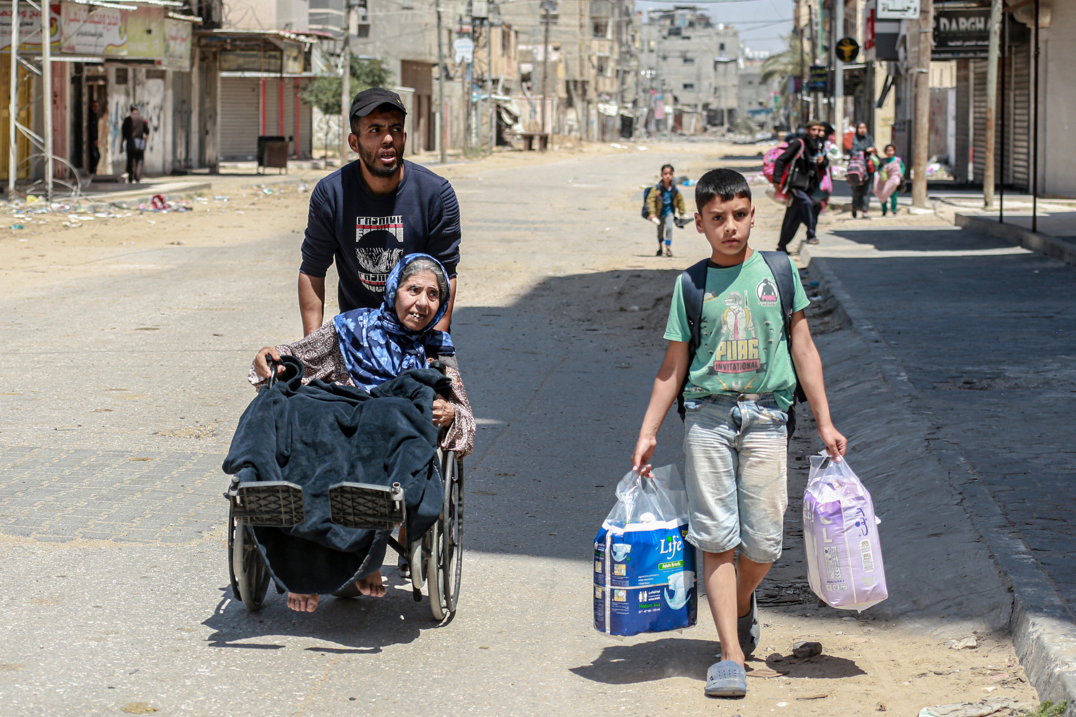 Palestinians carrying their personal belongings flee their homes in the city of Nuseirat in the central Gaza Strip