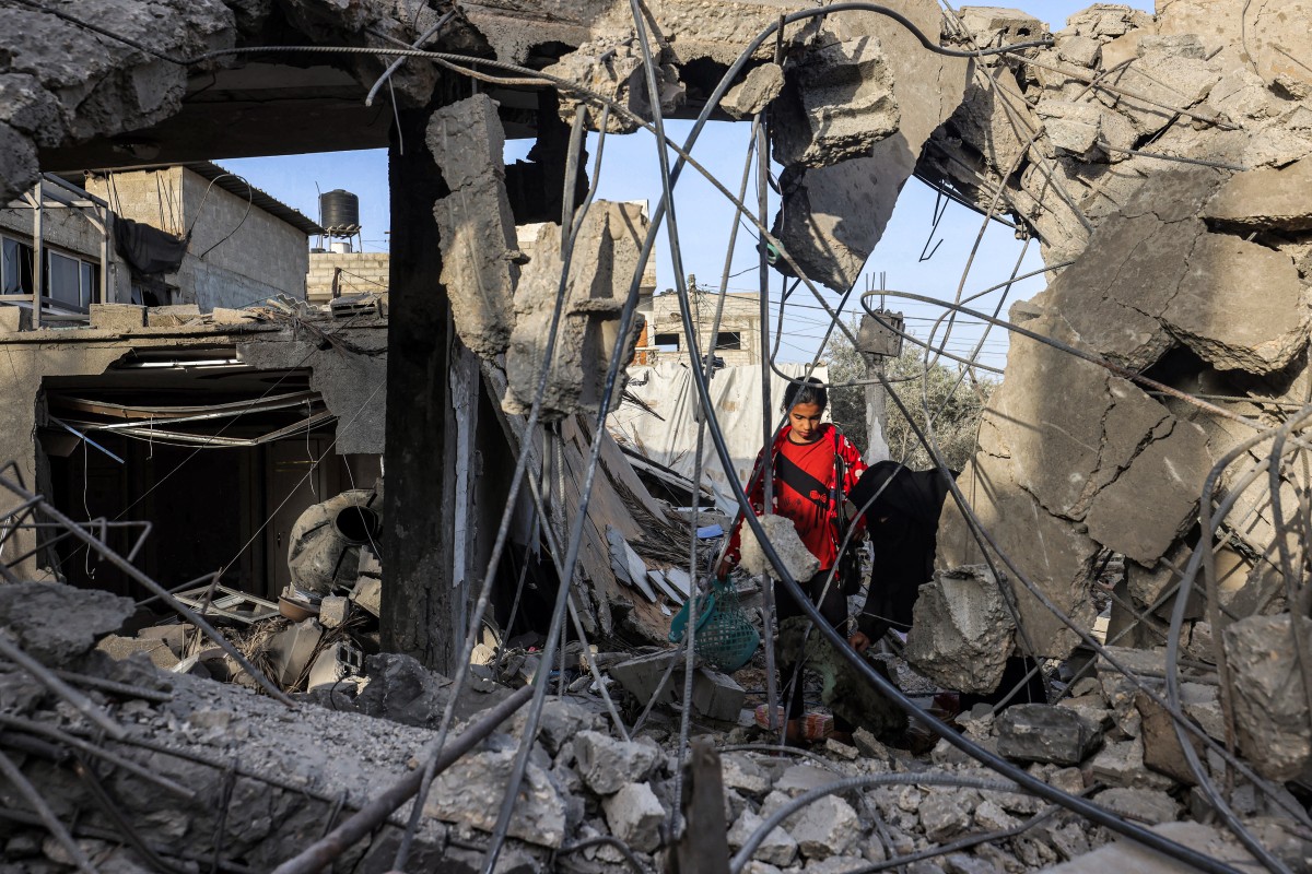 A woman and a girl search for items through the rubble of a collapsed building in Rafah